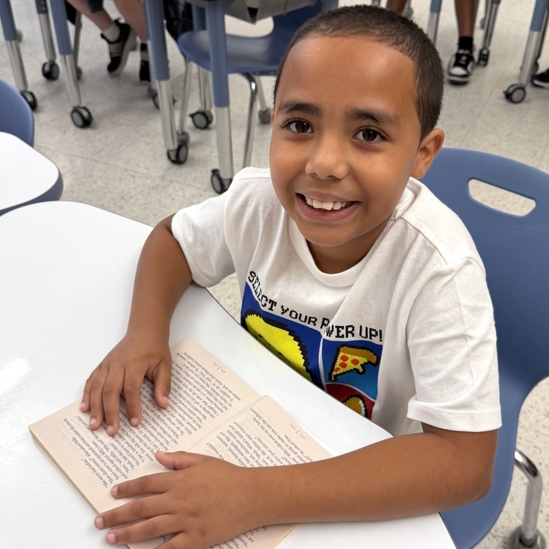 student at desk with book smiling