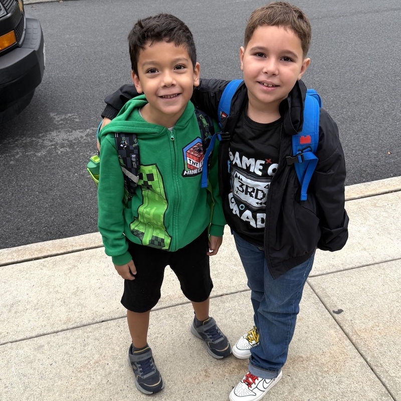 two boys outside on the sidewalk