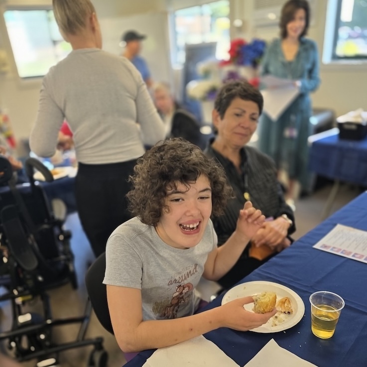 student laughs while eating breakfast as teacher looks on