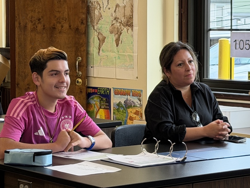 student and teacher sit at desk during lesson