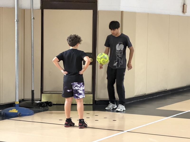 two boys juggling a soccer ball