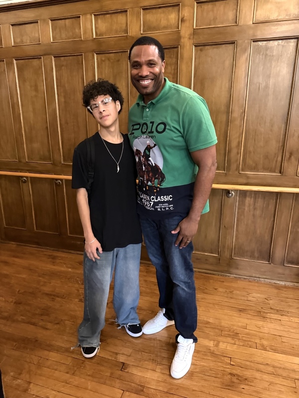 teacher and student smiling against wooden wall