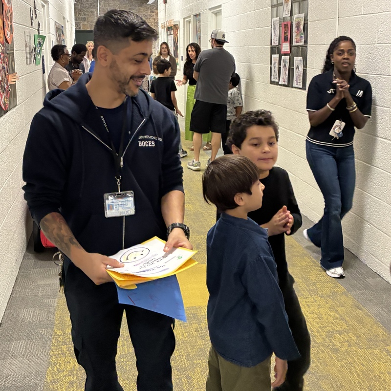 students and custodian walk down hallway