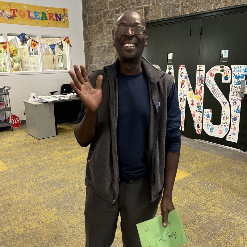 custodian smiles and waves in main hallway