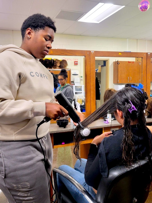 student practices styling technique on classmate