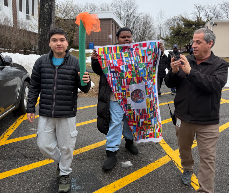 teacher and students carry olympic banner