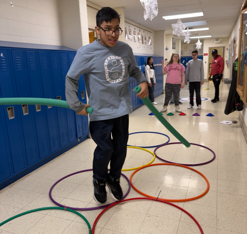 student jumps through rings in hallway olympic games