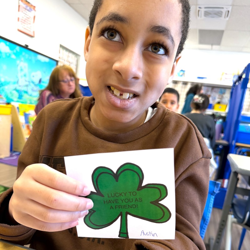 boy holds up shamrock craft he made