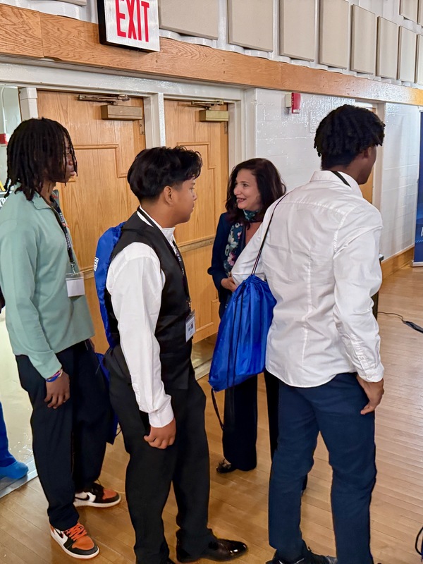 woman greats young men at symposium entrance