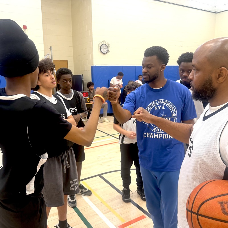 players and educators bump fists on basketball court