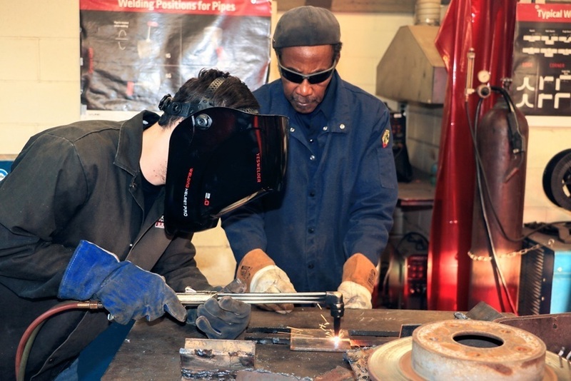 Student welder working under the supervision of an instructor