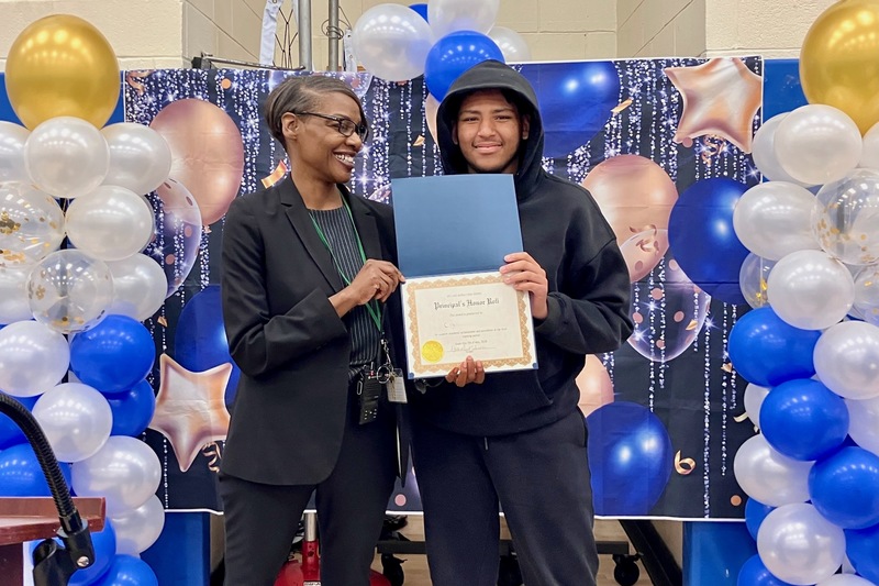 student holds certificate by principal