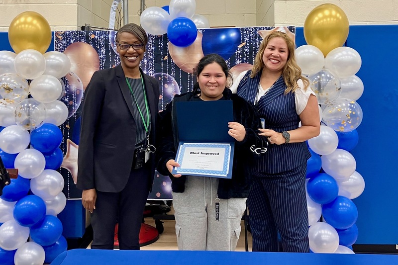 principl and counselor flank student holding certificate