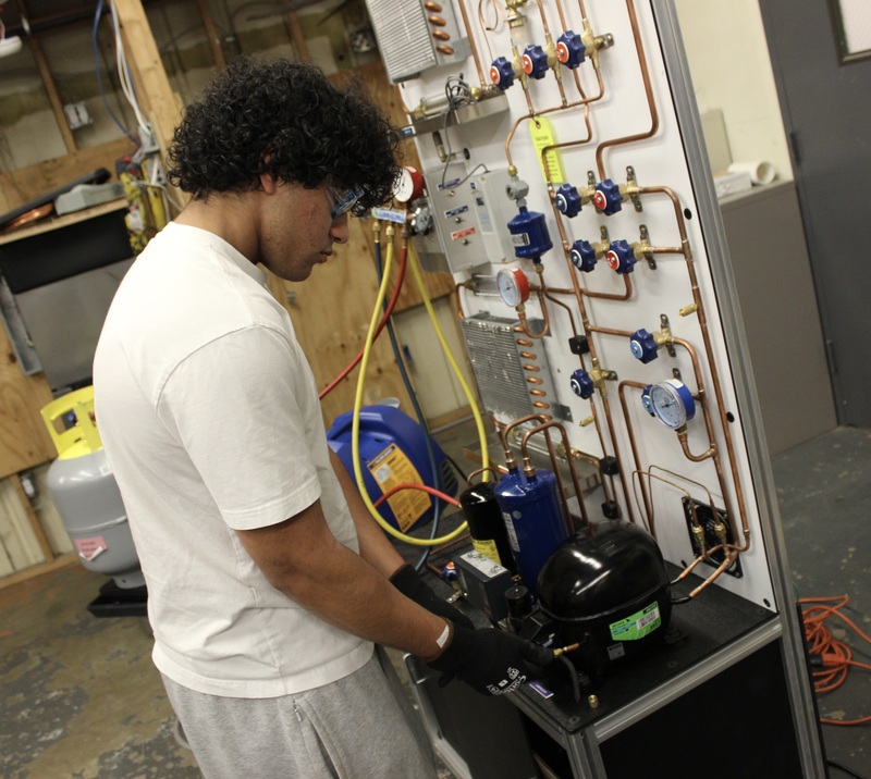 A HVAC student works on a refrigeration system.