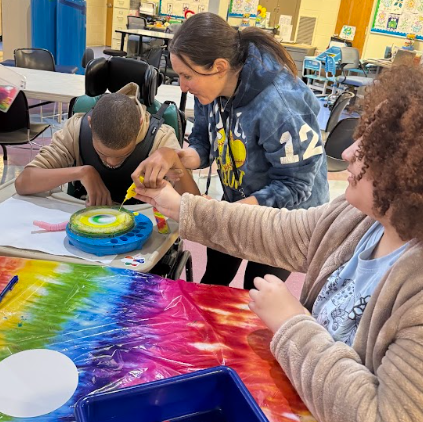 students assist one another with artwork