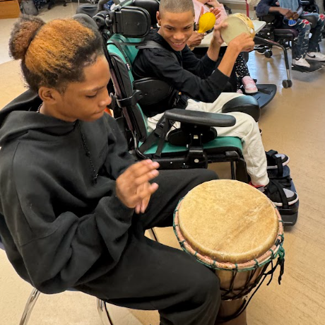 student plays bongo while another looks on