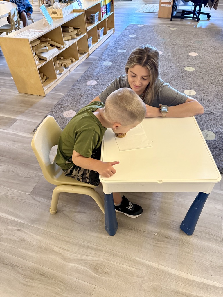 teacher smiling and child smelling cookie