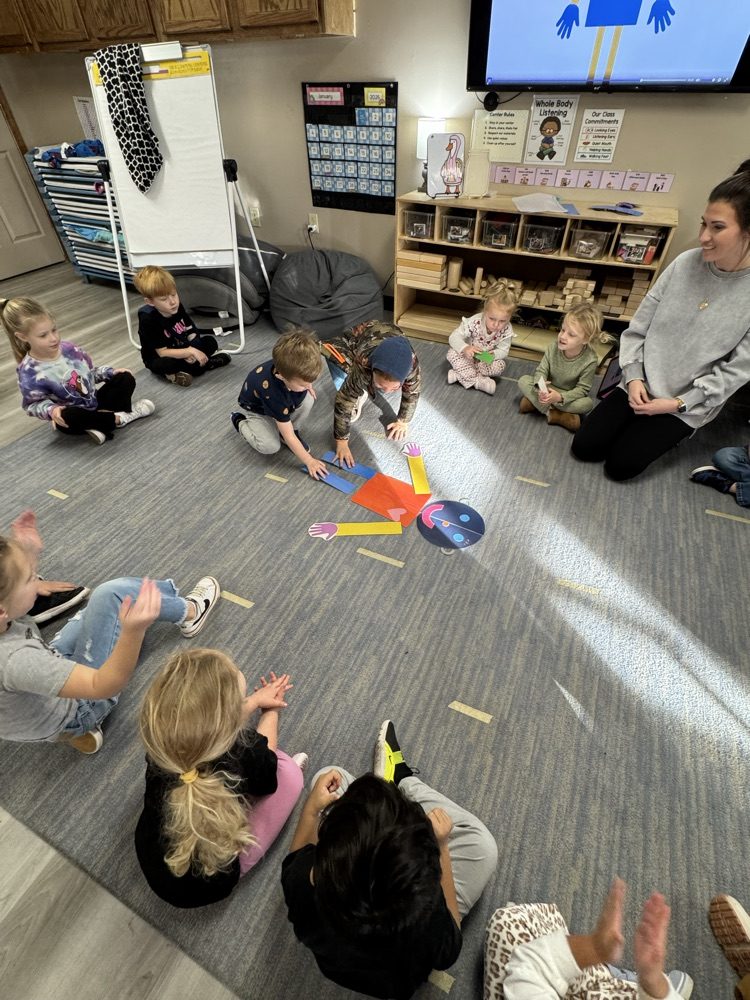 children placing paper body parts to build a person