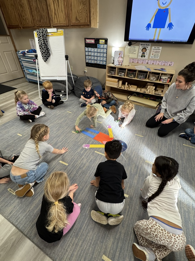 children placing paper body parts to build a person