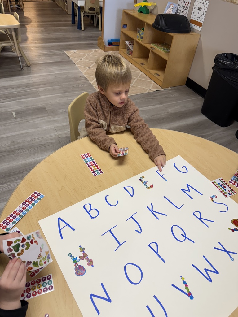 child placing stickers on letters