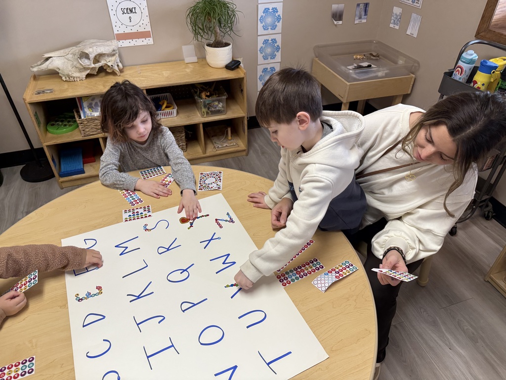 children placing stickers on letters
