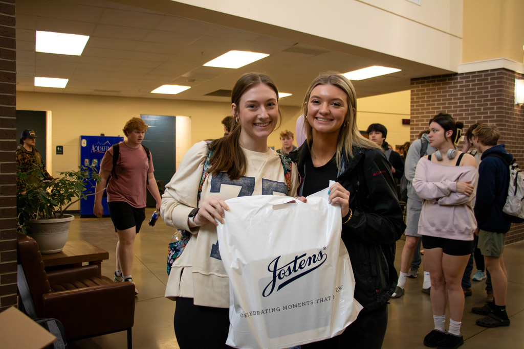 Two senior girls holding a Jostens bag