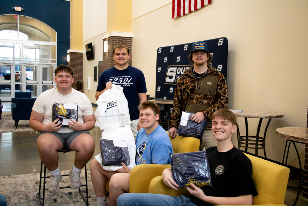 Five seniors holding their cap and gowns