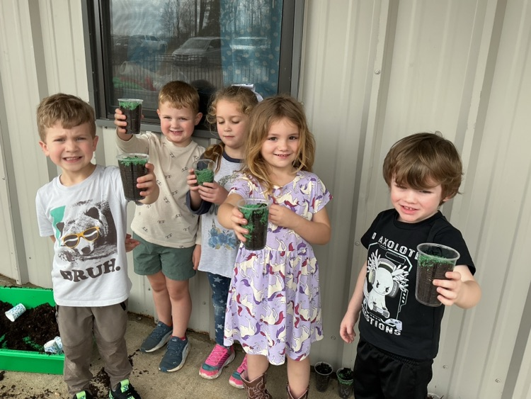 children showing cups of planted grass