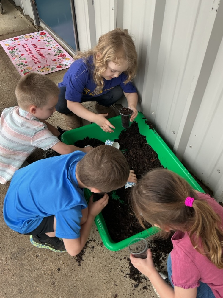 children putting soil in cups 