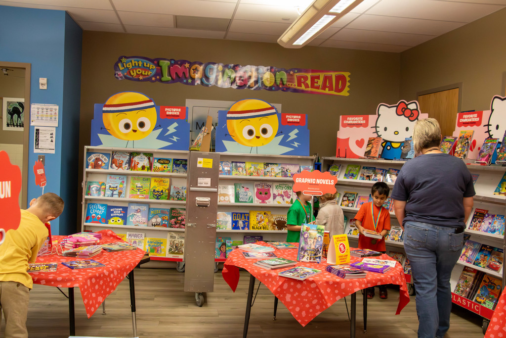 children and teacher looking at book fair