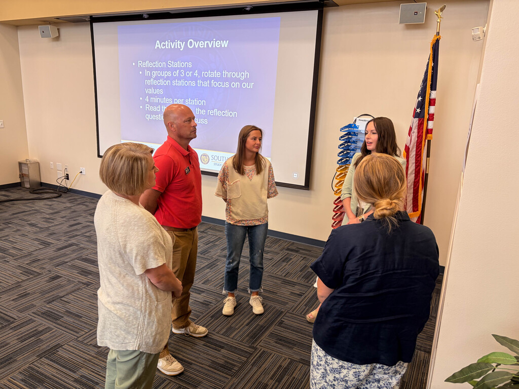 four women and a man in a circle speaking