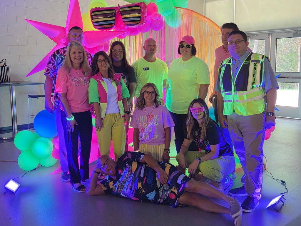 group of men and women in bright neon in front of glow in the dark balloons 