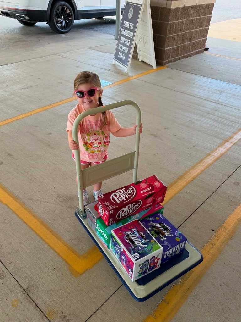 smiling child pushing cases of drinks on a dolly