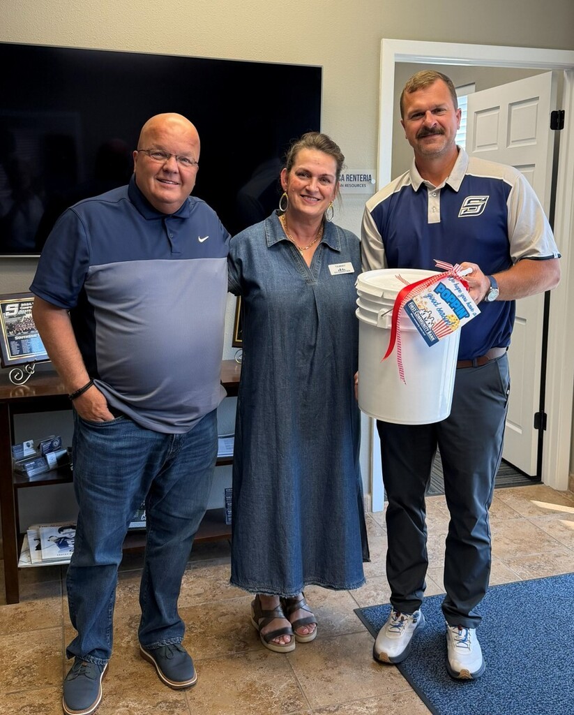 three smiling people holding a bucket of unpopped popcorn