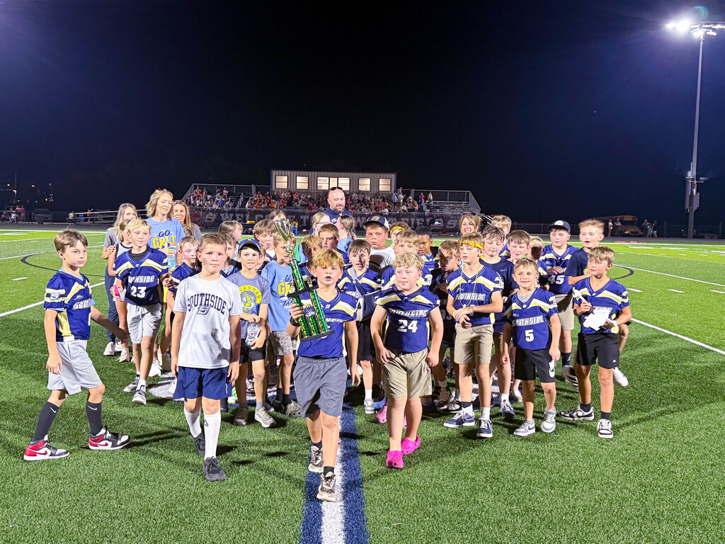 students in football jerseys holding trophy