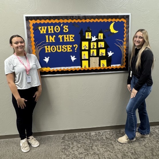 TP students stand next to the October bulletin board 