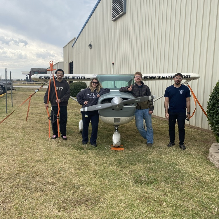 students posing happily with an airplane