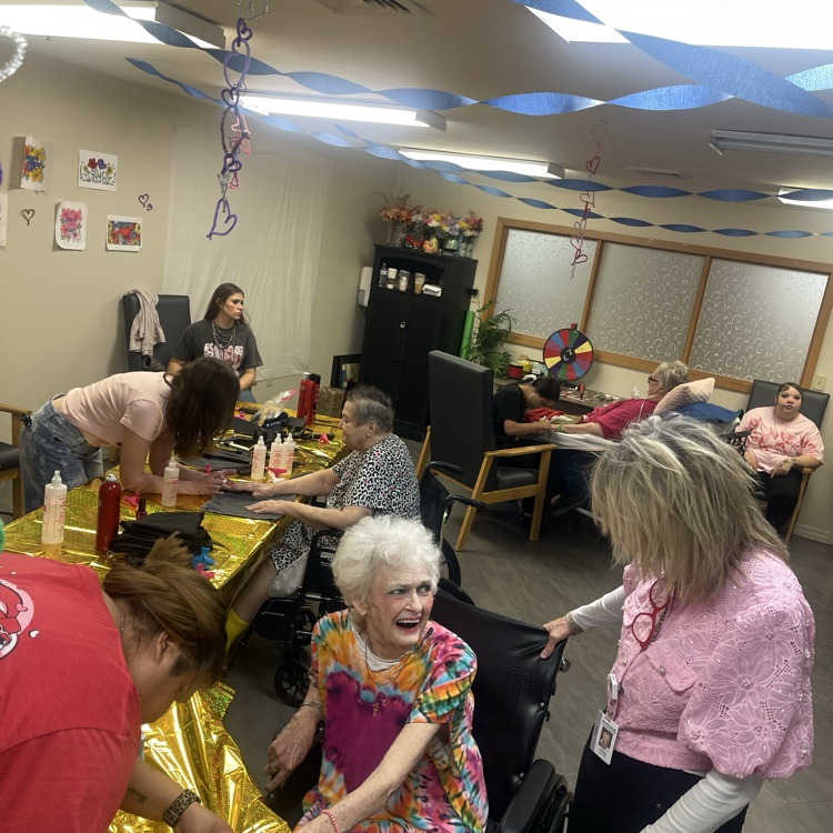 collect group of women applying nail polish to elderly women 