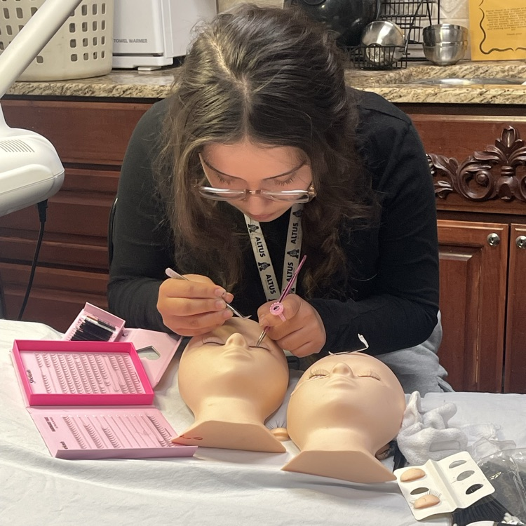 student doing lashes on face mannequin 