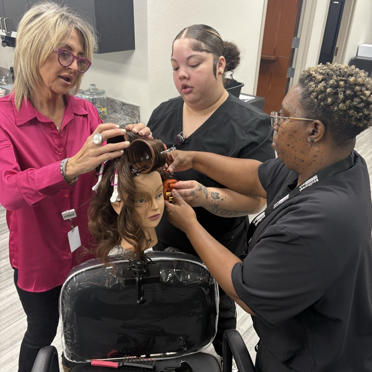 young women and instructor working on perm with plastic planter pots
