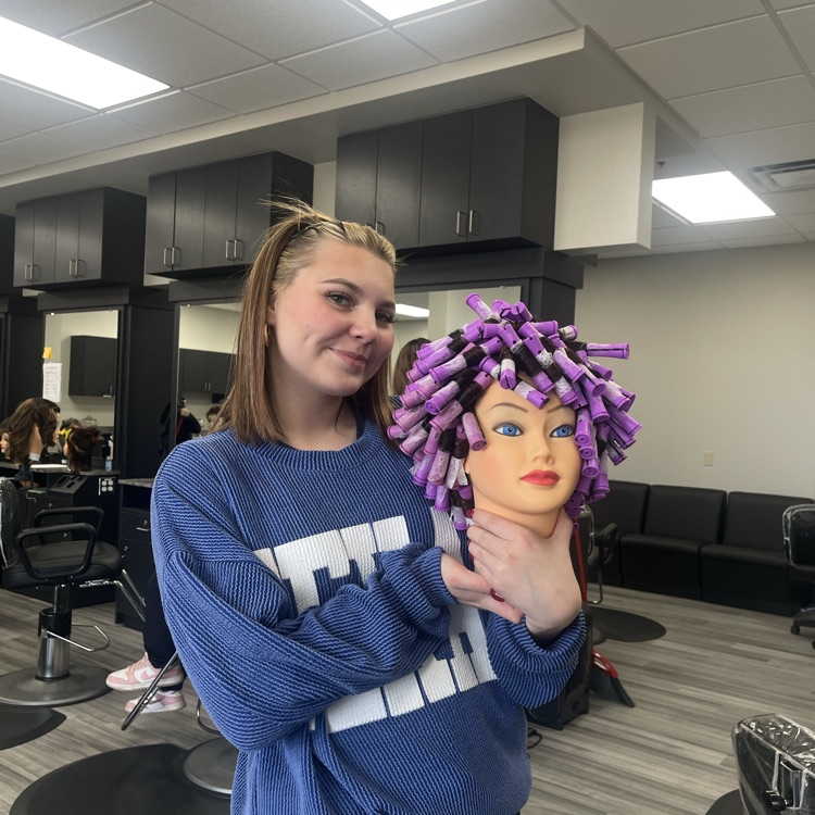 cosmetology student holding permed mannequin head
