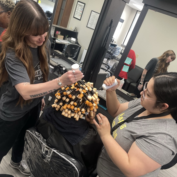 two Cosmo students working a perm on client 