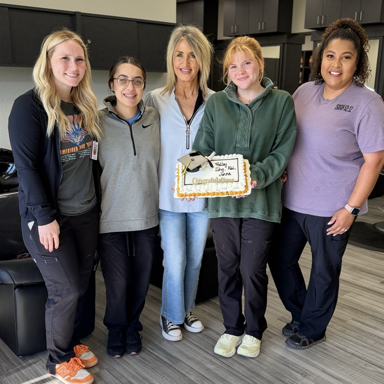 graduating cosmetology students with their teacher and a celebration cake