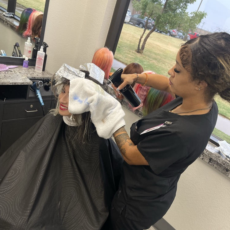 adult cosmetology student performing hair coloring service