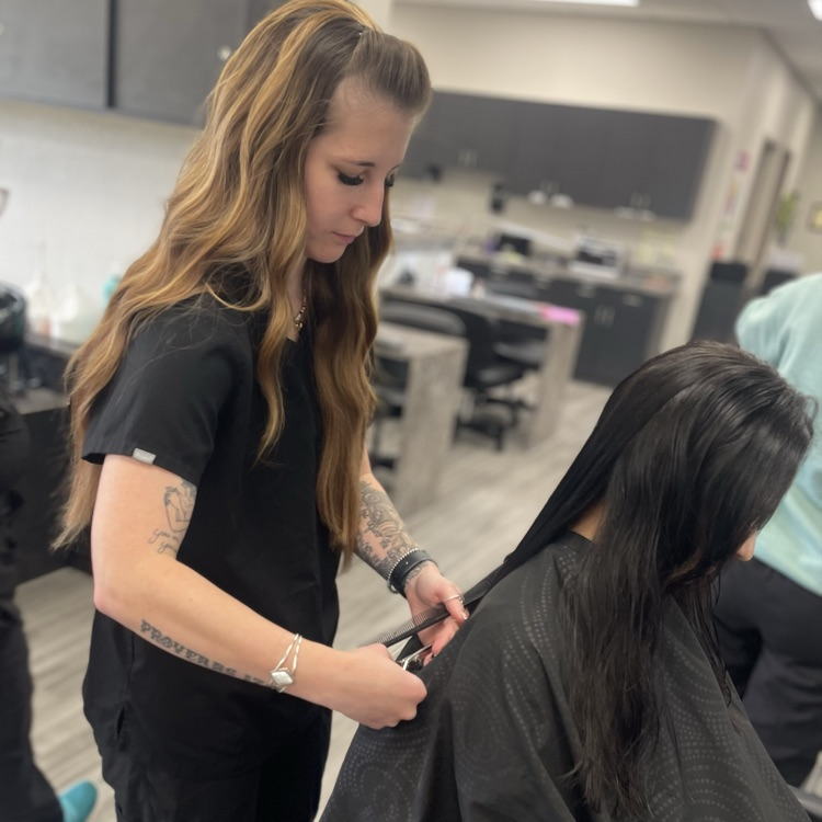 adult cosmetology student performing haircut