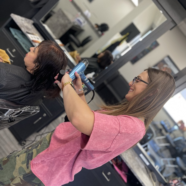 adult cosmetology student styling a client’s hair 