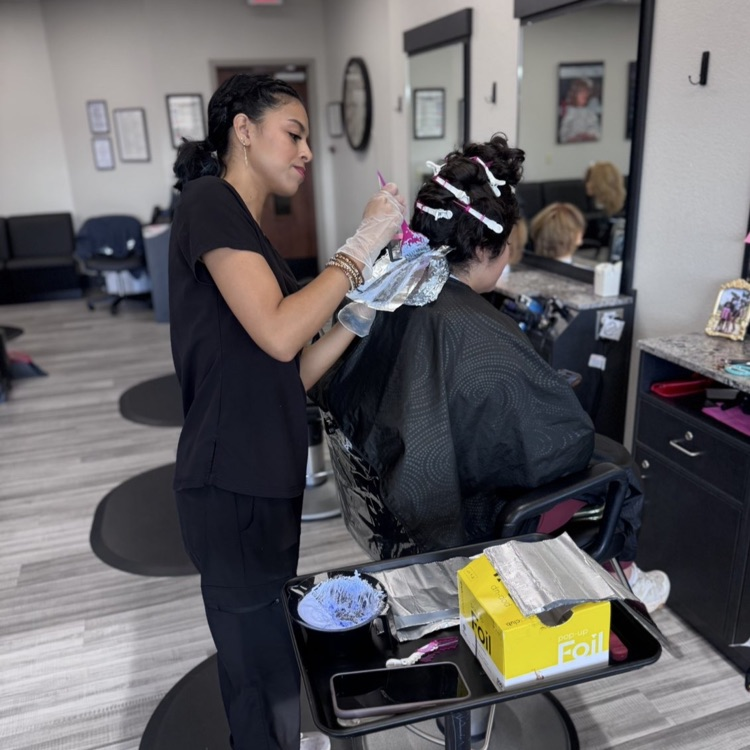 adult cosmetology student performing a hair color service 