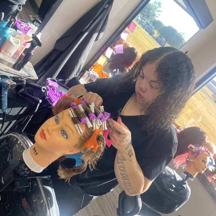 cosmetology student doing perm on mannequin hea
