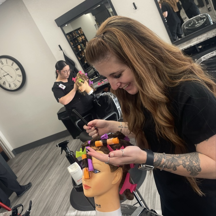 cosmetology student doing perm on mannequin hea