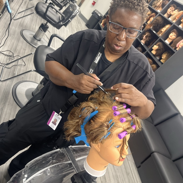 cosmetology student doing perm on mannequin hea